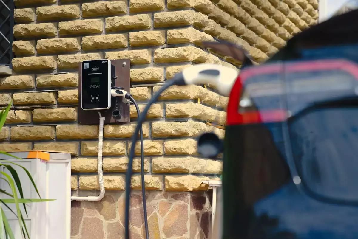 Foto van een wallbox aan een muur die een auto oplaadt.