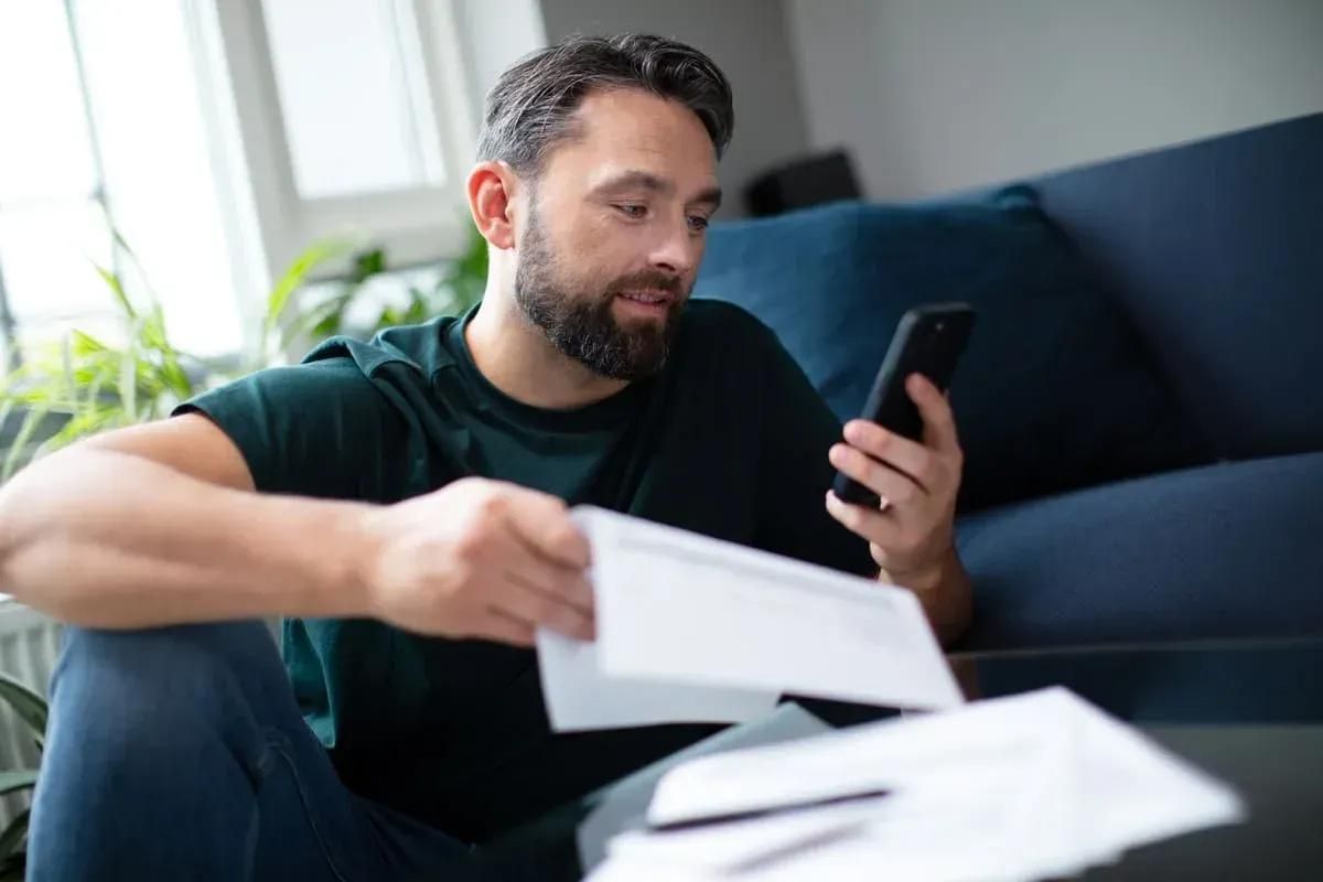 Man met een smartphone en een factuur